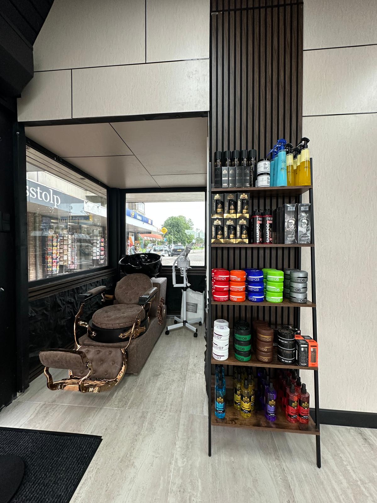 De wastafels met bruine leren stoelen en een plank vol haarproducten bij het raam